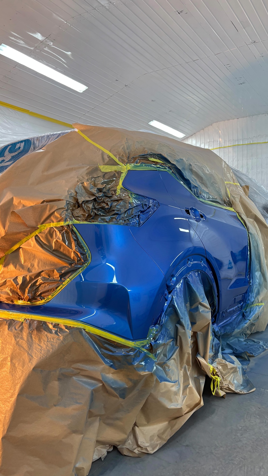 Veículo azul mascarado e preparado para pintura dentro da cabine.