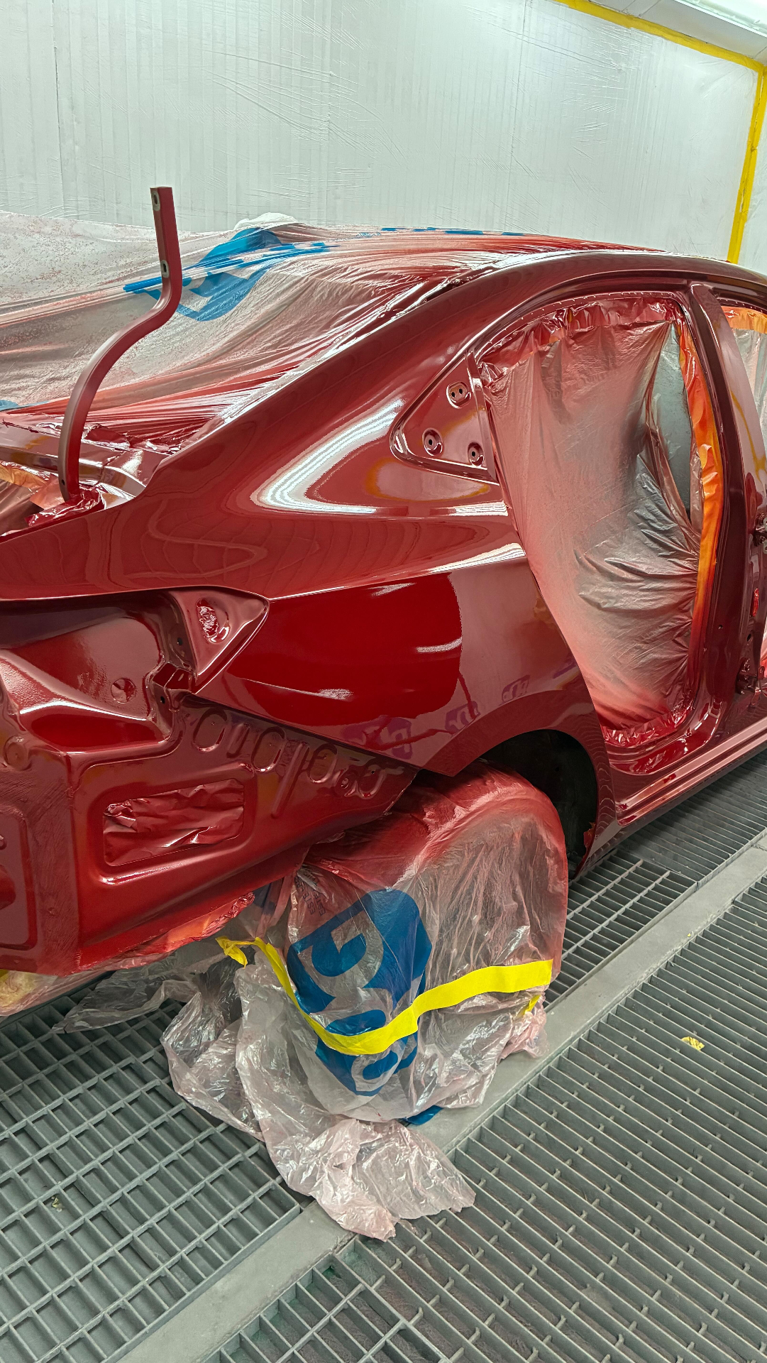 Veículo vermelho recém-pintado em cabine com acabamento brilhante.